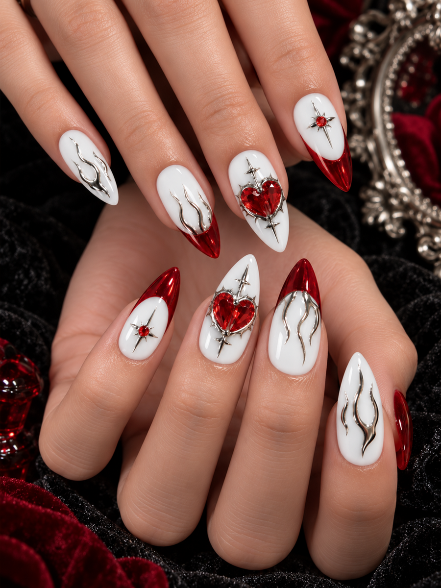 Ivory almond nails with ruby red chrome French tips, 3D sacred heart gems, silver flame lines, and gothic cross accents