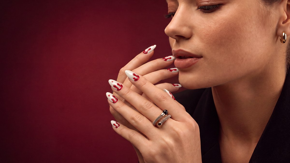 Long ivory almond nails with glossy cat-eye red blood-drip nail art for a bold vampire-inspired Halloween manicure
