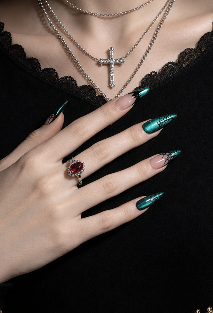 Emerald-green, mirror-finish stiletto nails featuring black spiderweb and bat-wing French tip designs create a Gothic look that is both bold and elegant.