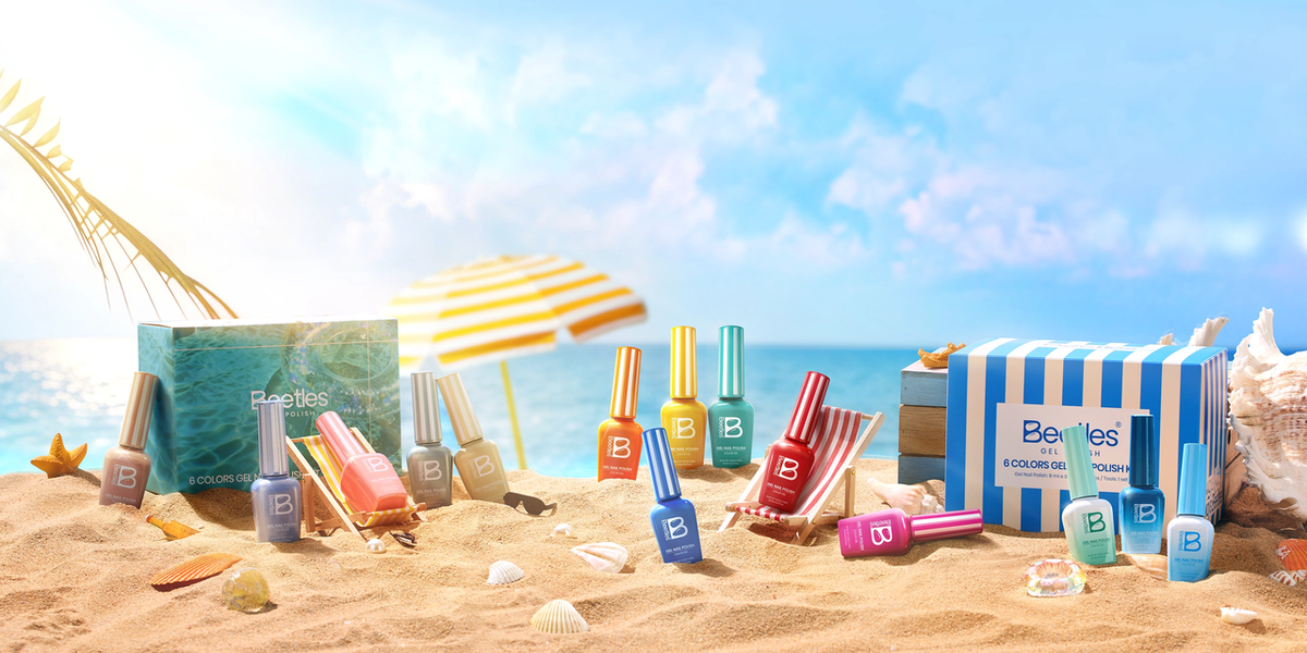 Beetles gel nail polish kits displayed on mini beach loungers on a sandy beach with turquoise ocean, seashells, and palm fronds — summer vacation lifestyle flat lay